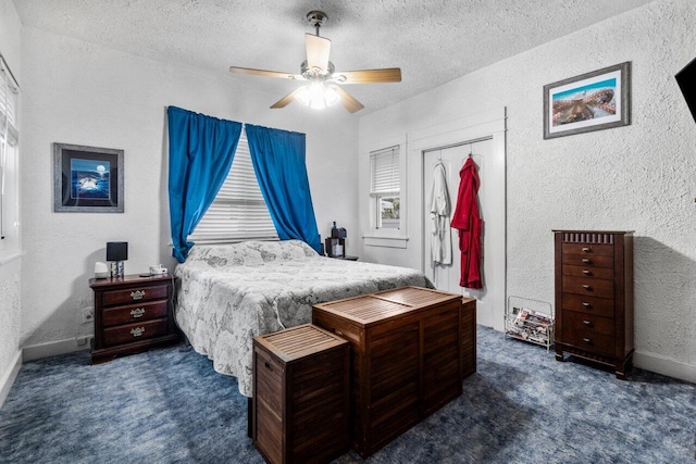 bedroom with a textured ceiling, dark carpet, a closet, and ceiling fan