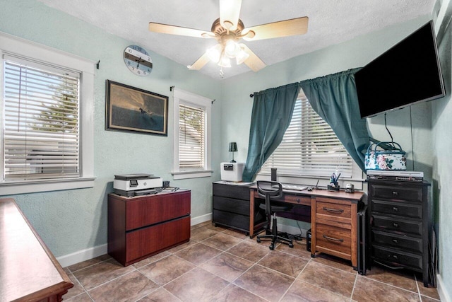 tiled office space featuring plenty of natural light, ceiling fan, and a textured ceiling