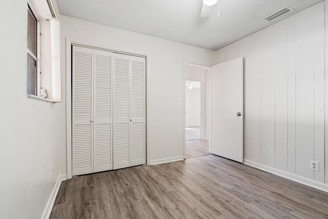 unfurnished bedroom with light hardwood / wood-style flooring, a closet, and ceiling fan