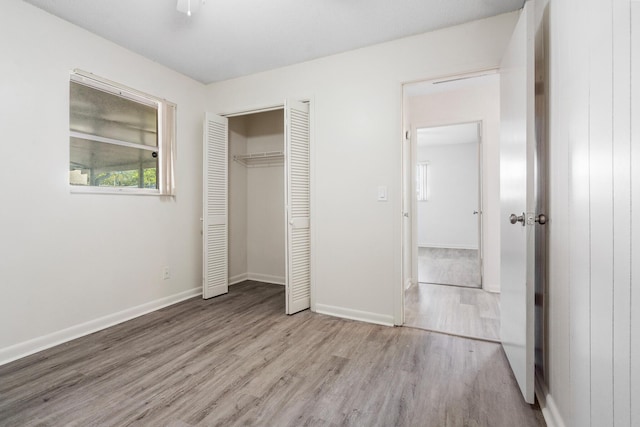 unfurnished bedroom with ceiling fan, a closet, and light wood-type flooring