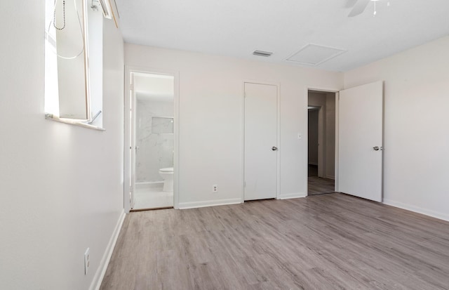 unfurnished bedroom with ceiling fan, ensuite bath, and light wood-type flooring