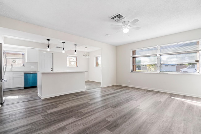 unfurnished living room with wood-type flooring, sink, ceiling fan with notable chandelier, and a textured ceiling