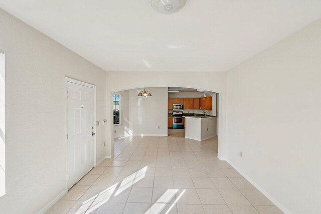 unfurnished living room featuring light tile patterned floors and a chandelier