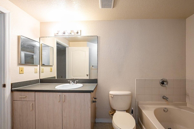 bathroom with vanity, a textured ceiling, toilet, and a bathtub