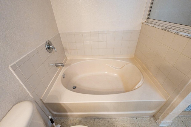 bathroom featuring tile patterned flooring, toilet, and a tub