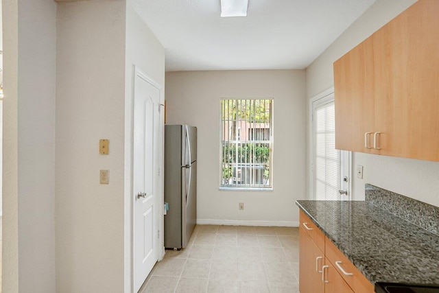 kitchen with stainless steel fridge and dark stone counters