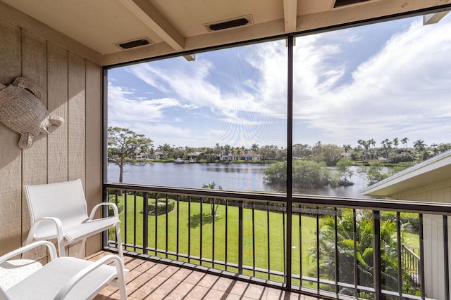 sunroom with a healthy amount of sunlight, a water view, and beam ceiling