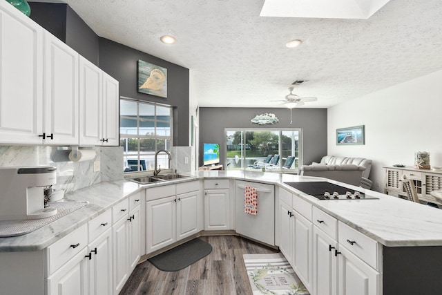 kitchen featuring a textured ceiling, black electric cooktop, sink, dishwasher, and white cabinetry