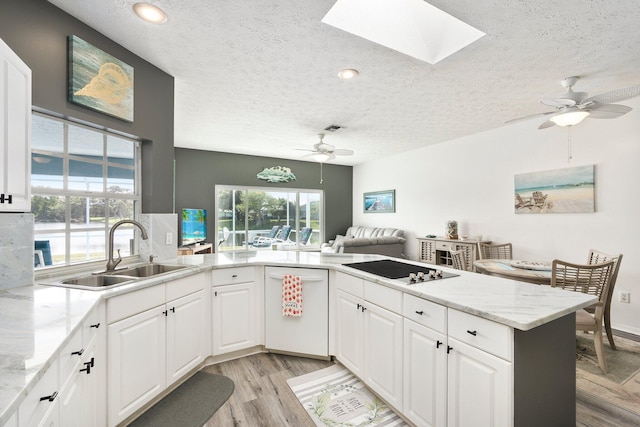 kitchen with a skylight, white cabinetry, sink, kitchen peninsula, and a textured ceiling