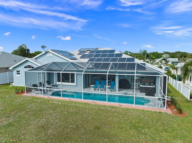 back of house with solar panels, a patio area, a yard, and glass enclosure