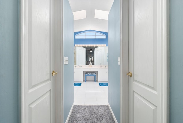 hallway with light tile patterned flooring and vaulted ceiling