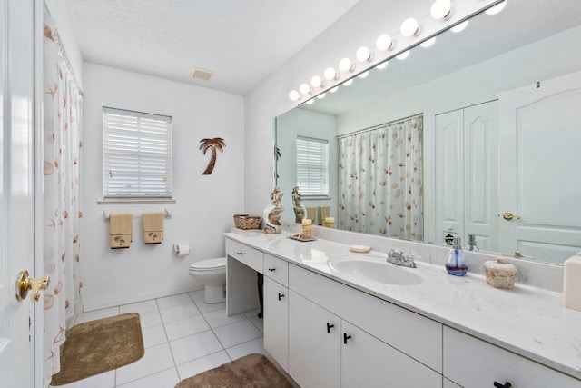 bathroom with tile patterned floors, vanity, a textured ceiling, and toilet