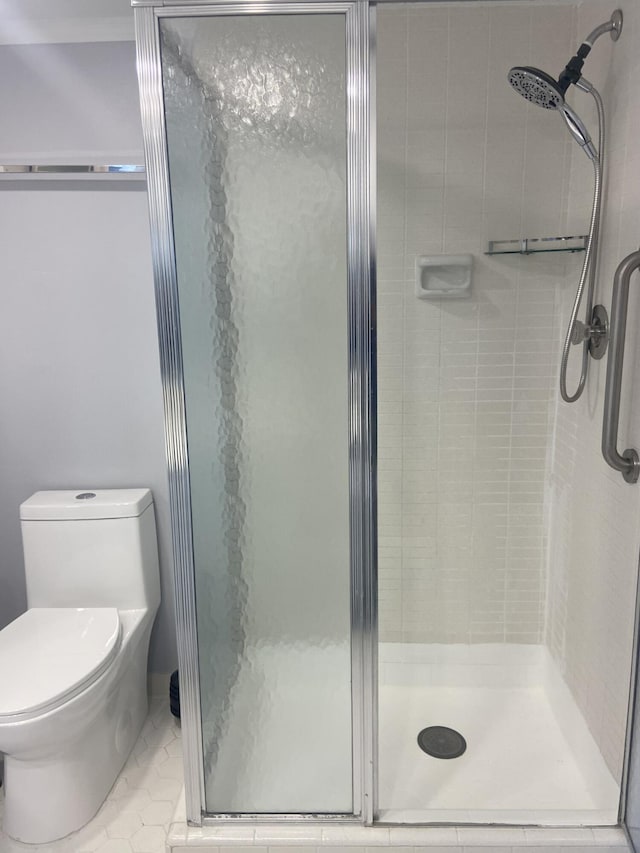 bathroom featuring tile patterned floors, toilet, and a shower with shower door