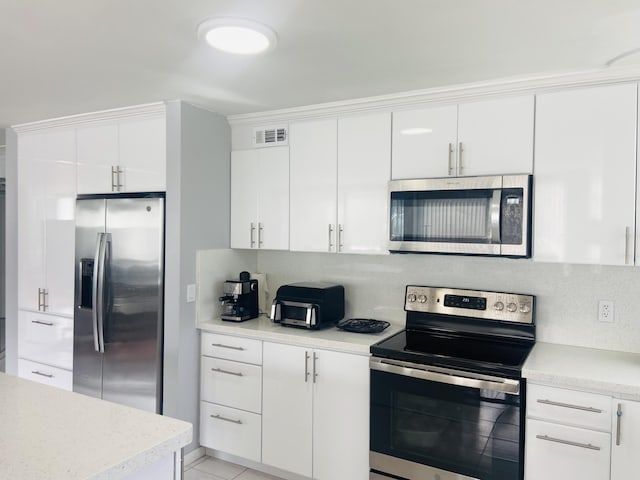 kitchen featuring white cabinets, light tile patterned flooring, appliances with stainless steel finishes, and tasteful backsplash