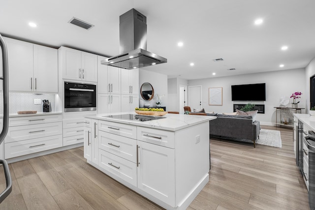 kitchen featuring white cabinetry, island range hood, light wood-type flooring, black appliances, and a center island