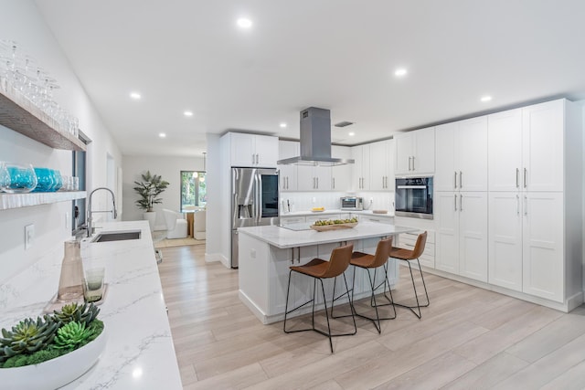 kitchen with white cabinets, sink, stainless steel fridge with ice dispenser, island range hood, and oven