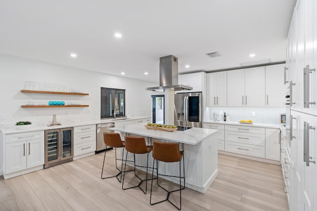 kitchen featuring a kitchen island, white cabinetry, stainless steel appliances, wine cooler, and island range hood