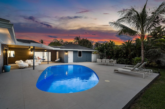 pool at dusk with an outdoor hangout area and a patio area