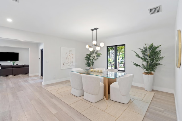 dining space with light hardwood / wood-style flooring and an inviting chandelier