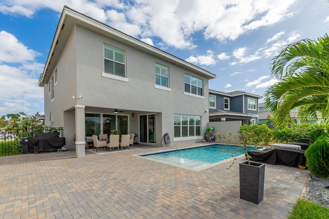 view of pool featuring outdoor lounge area, pool water feature, ceiling fan, grilling area, and a patio area