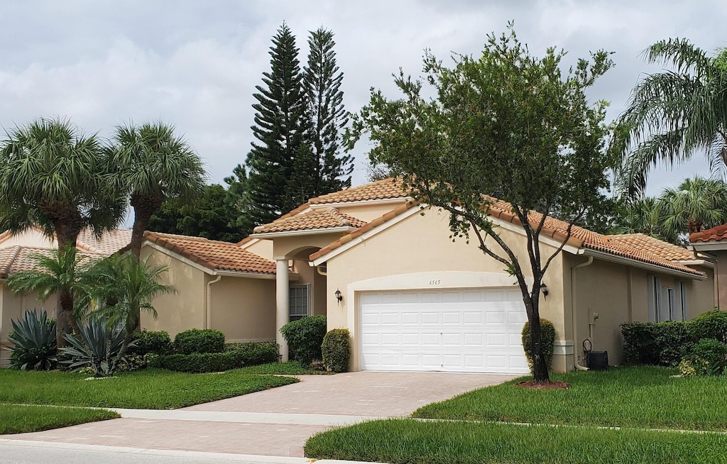 mediterranean / spanish home with a garage and a front lawn