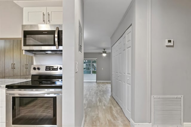 kitchen featuring light stone countertops, white cabinets, appliances with stainless steel finishes, light hardwood / wood-style floors, and ceiling fan