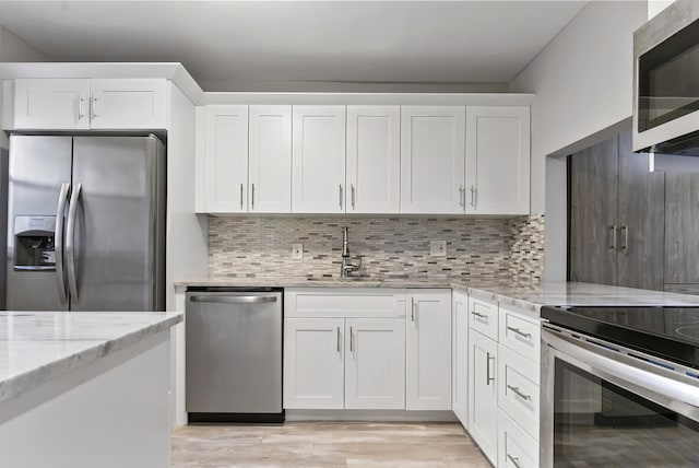 kitchen with stainless steel appliances, decorative backsplash, white cabinetry, and sink