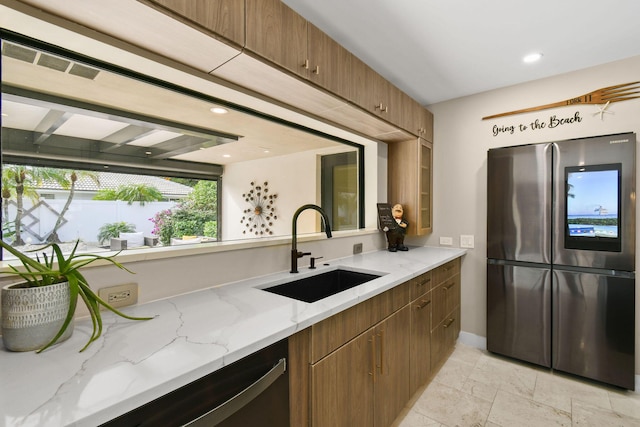 kitchen with stainless steel appliances, light stone counters, and sink