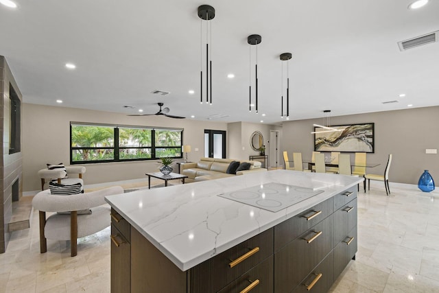 kitchen featuring a large island, light stone countertops, ceiling fan, pendant lighting, and white electric stovetop