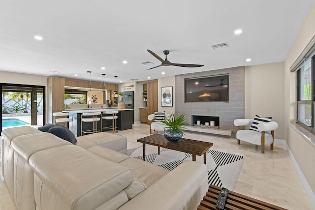 tiled living room featuring ceiling fan and a large fireplace