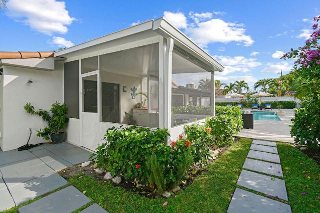 view of side of property featuring a patio area and a sunroom