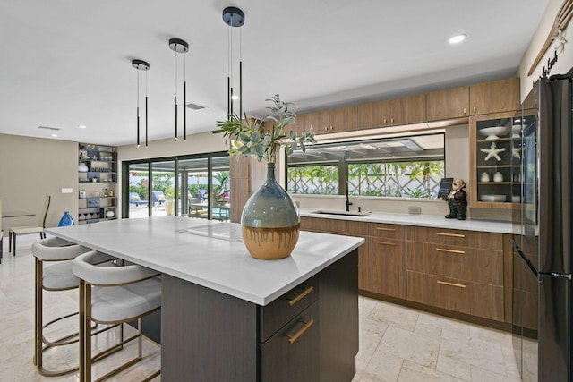 kitchen with a kitchen breakfast bar, black fridge, sink, decorative light fixtures, and a kitchen island