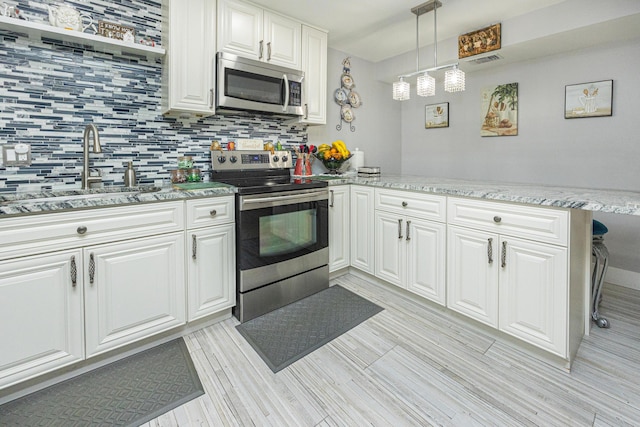 kitchen featuring white cabinetry, sink, kitchen peninsula, decorative light fixtures, and appliances with stainless steel finishes