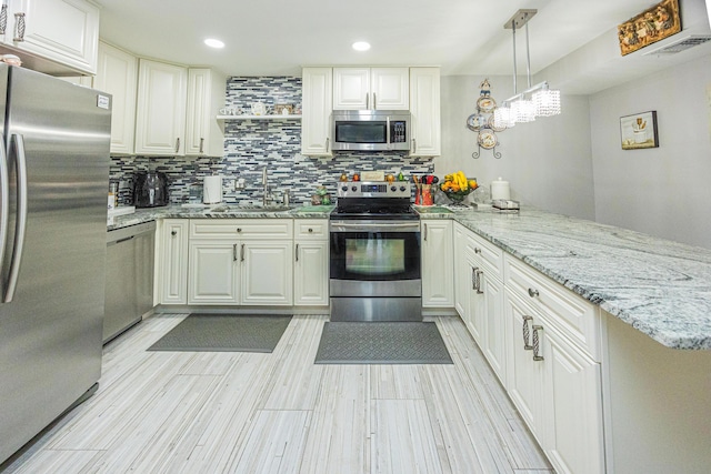 kitchen with sink, stainless steel appliances, light stone counters, kitchen peninsula, and decorative light fixtures