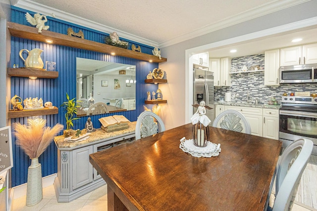 tiled dining area featuring a textured ceiling, ornamental molding, and sink