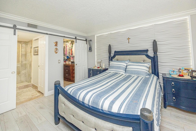 bedroom with a textured ceiling, a barn door, crown molding, and a closet