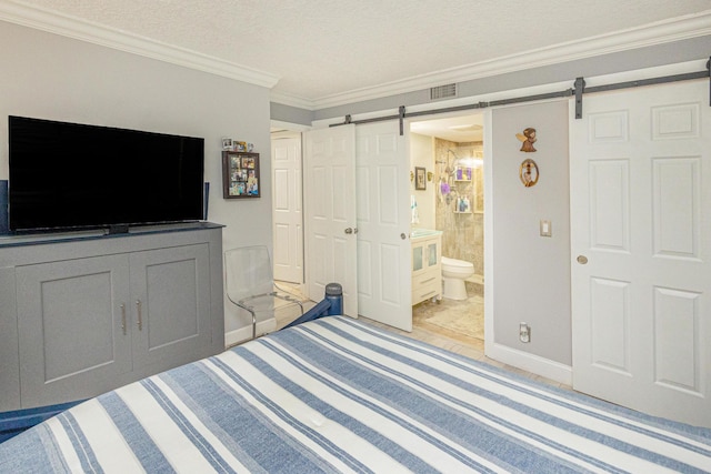 bedroom featuring ensuite bath, a textured ceiling, crown molding, a barn door, and a closet