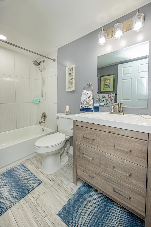 full bathroom featuring tiled shower / bath, vanity, and toilet