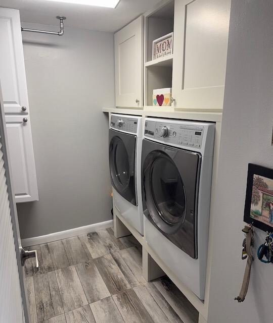 laundry room featuring cabinets, washing machine and dryer, and light wood-type flooring