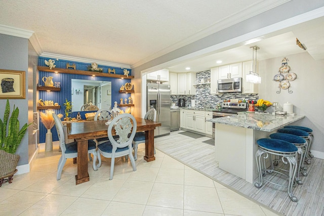 kitchen featuring pendant lighting, white cabinetry, kitchen peninsula, and stainless steel appliances