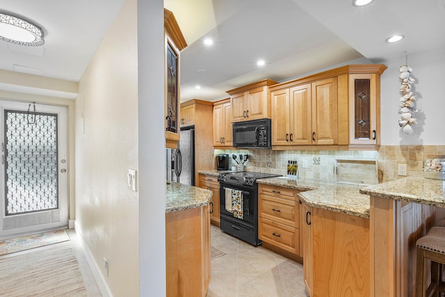 kitchen featuring a kitchen breakfast bar, tasteful backsplash, light stone counters, kitchen peninsula, and black appliances