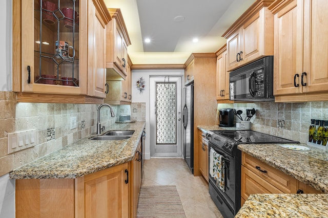 kitchen featuring light stone countertops, sink, tasteful backsplash, light tile patterned floors, and black appliances