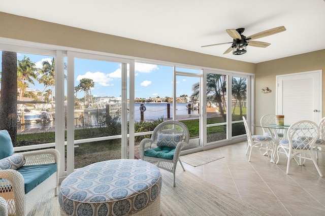 sunroom / solarium with a wealth of natural light, ceiling fan, and a water view