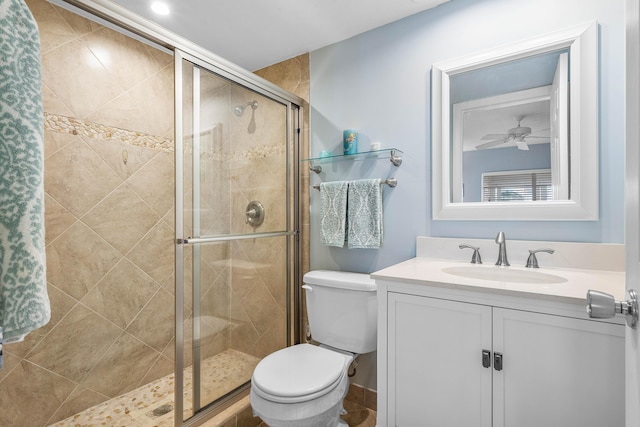 bathroom with vanity, toilet, a shower with door, and ceiling fan