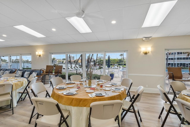 dining space with a drop ceiling and light wood-type flooring