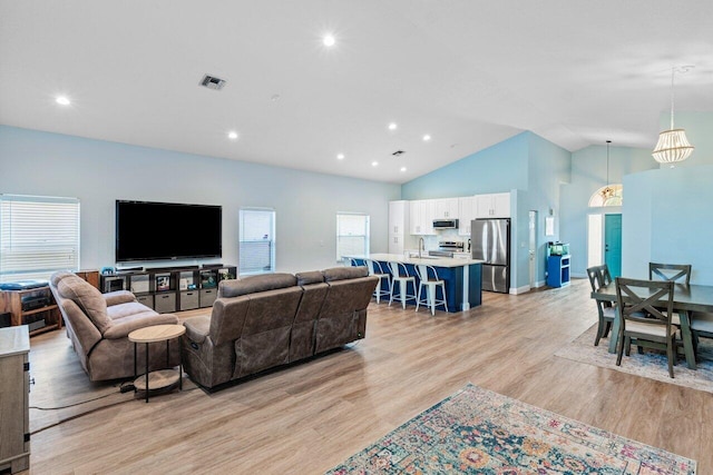 living room featuring light hardwood / wood-style floors, sink, and vaulted ceiling