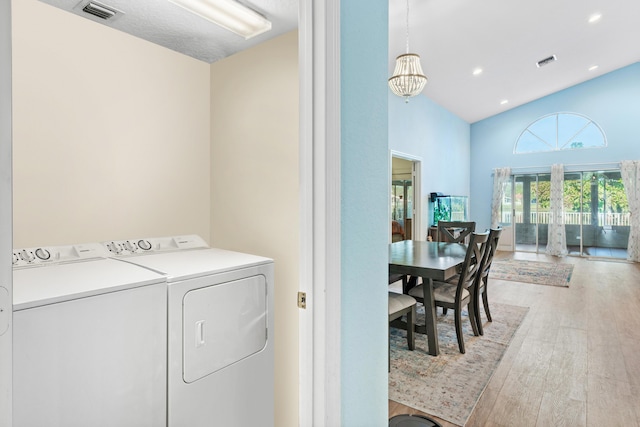 washroom featuring hardwood / wood-style floors, a notable chandelier, and washing machine and clothes dryer