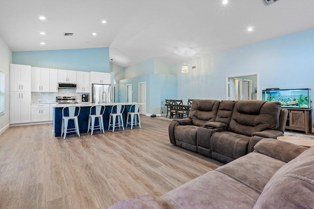 living room with light wood-type flooring and high vaulted ceiling