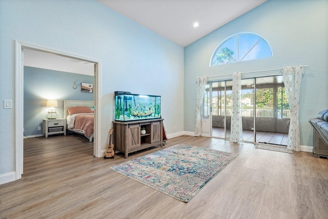 bedroom with high vaulted ceiling and light hardwood / wood-style flooring