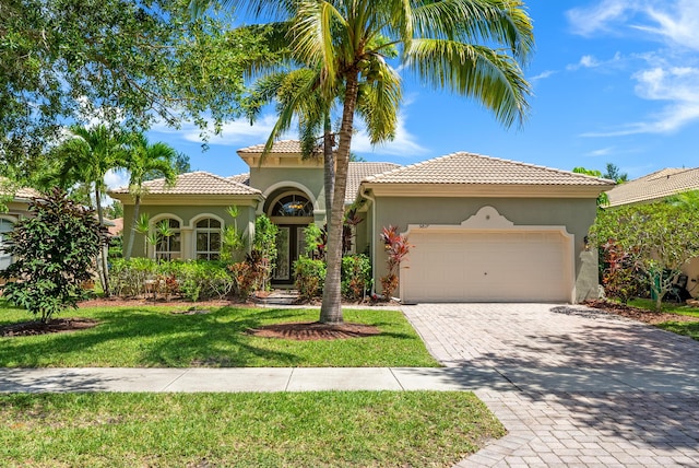 mediterranean / spanish home with a garage and a front lawn